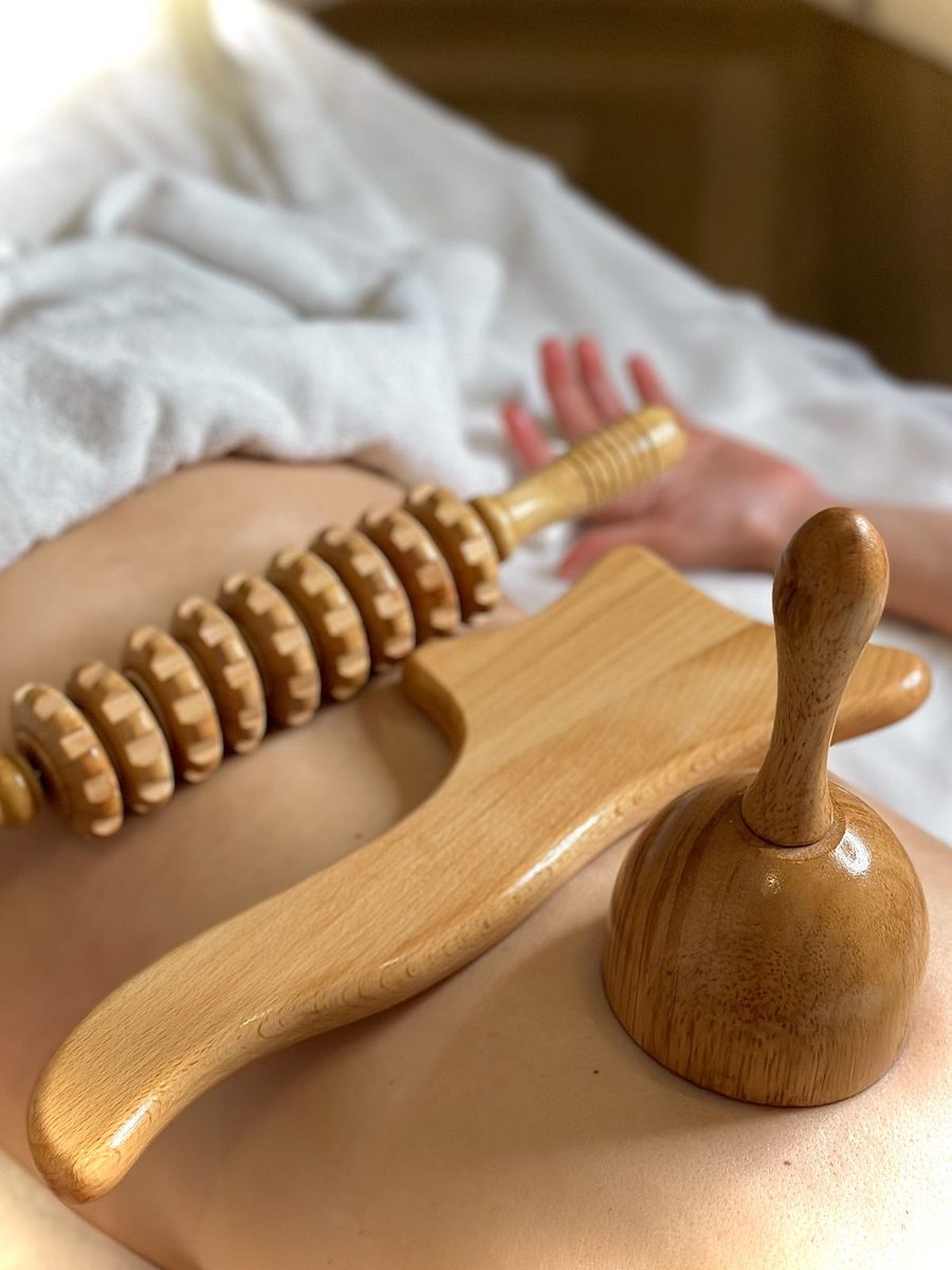 Outils de madérothérapie en bois posés sur le dos d'une cliente.