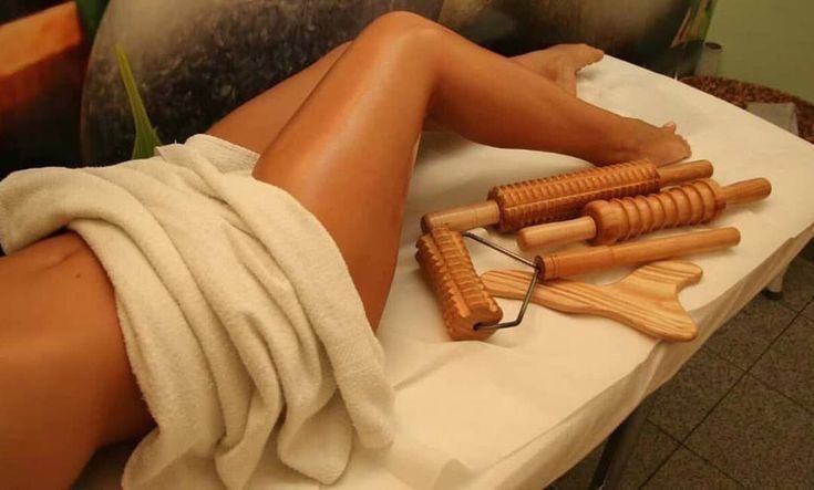 Des outils de madérothérapie posés près des jambes d'une cliente.
