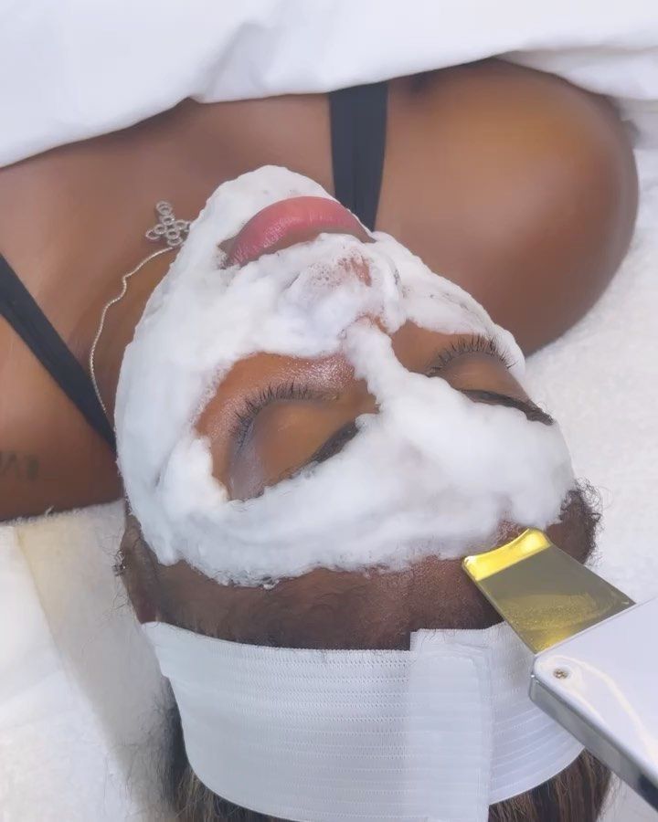 Un masque moussant sur le visage d'une cliente, près d'une spatule à ultrasons.