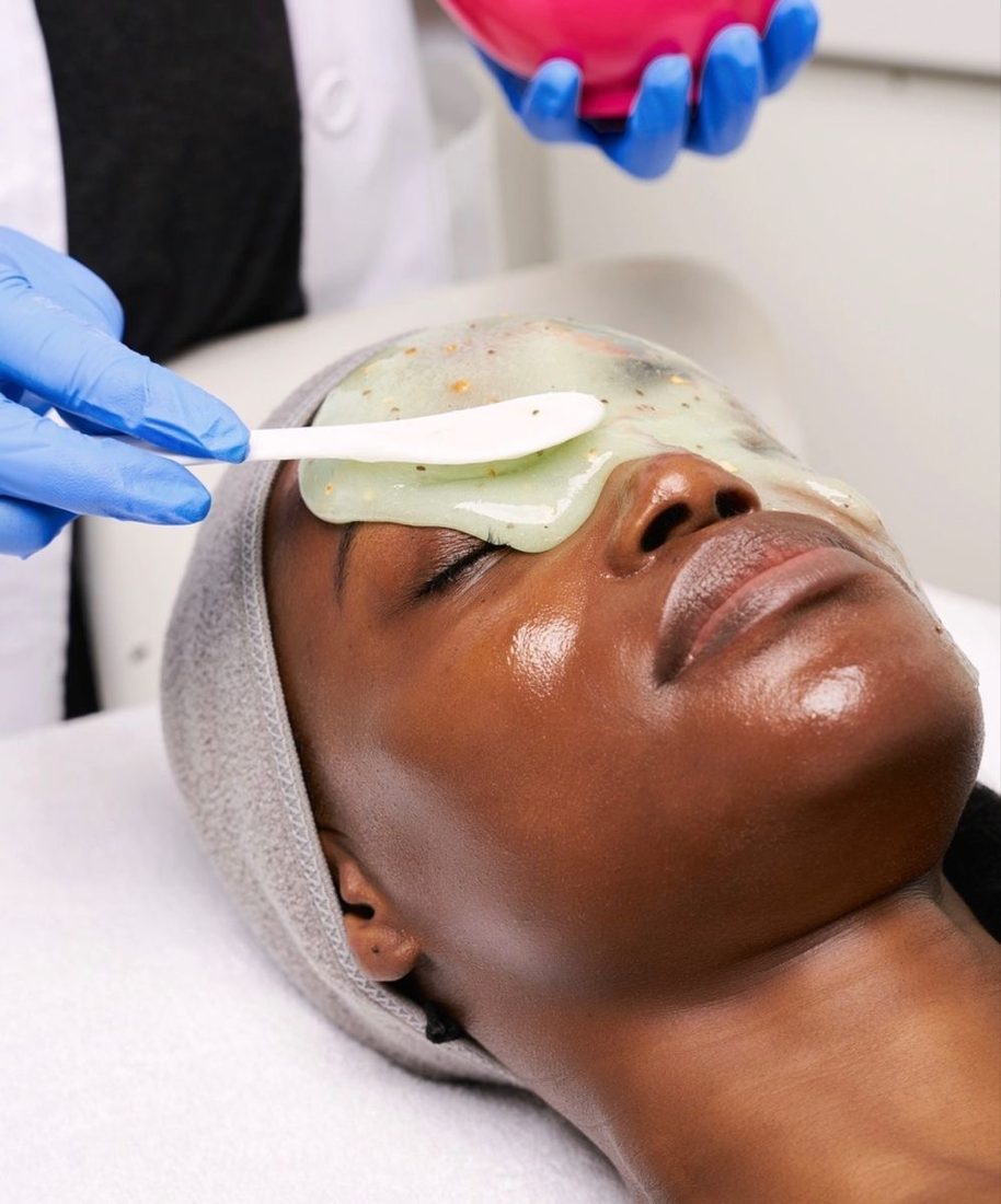 Un masque en gel vert appliqué à la spatule sur le haut du visage d'une cliente.