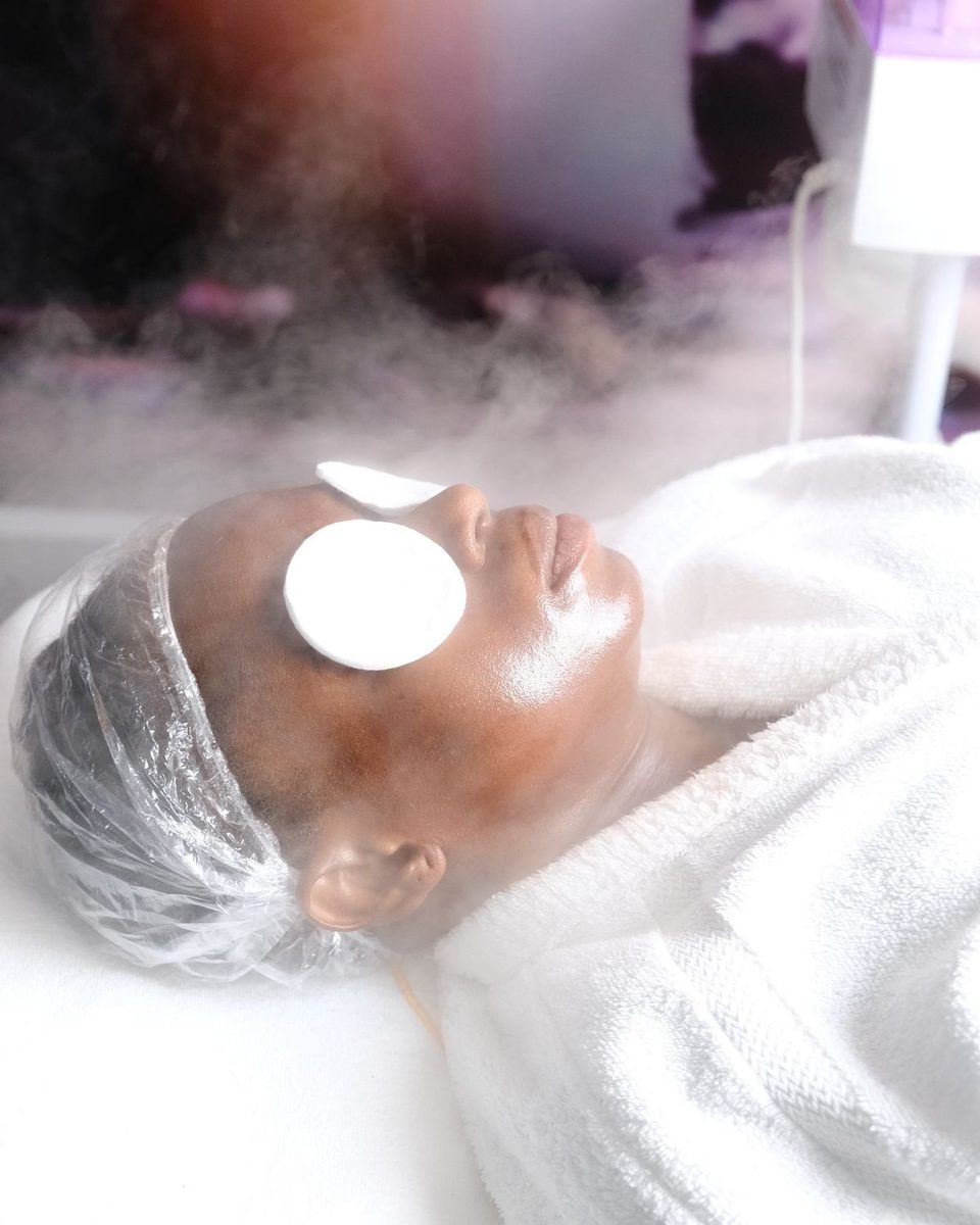 Une cliente allongée, des cotons sur les yeux, le visage enveloppé de vapeur.